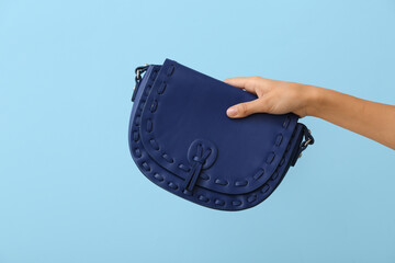 Poster - Female hand with stylish blue bag on color background