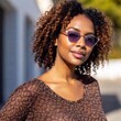 © LIGHTFIELD STUDIOS - A close-up photo of a multiracial female adult with sunglasses reflecting the radiant sun, deep focus on her relaxed face and the soft glow of sunlight on her skin, eye-level shot highlighting her