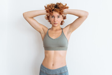 Portrait of a young woman with an athletic build, wearing a sports top, showing off her muscular arms