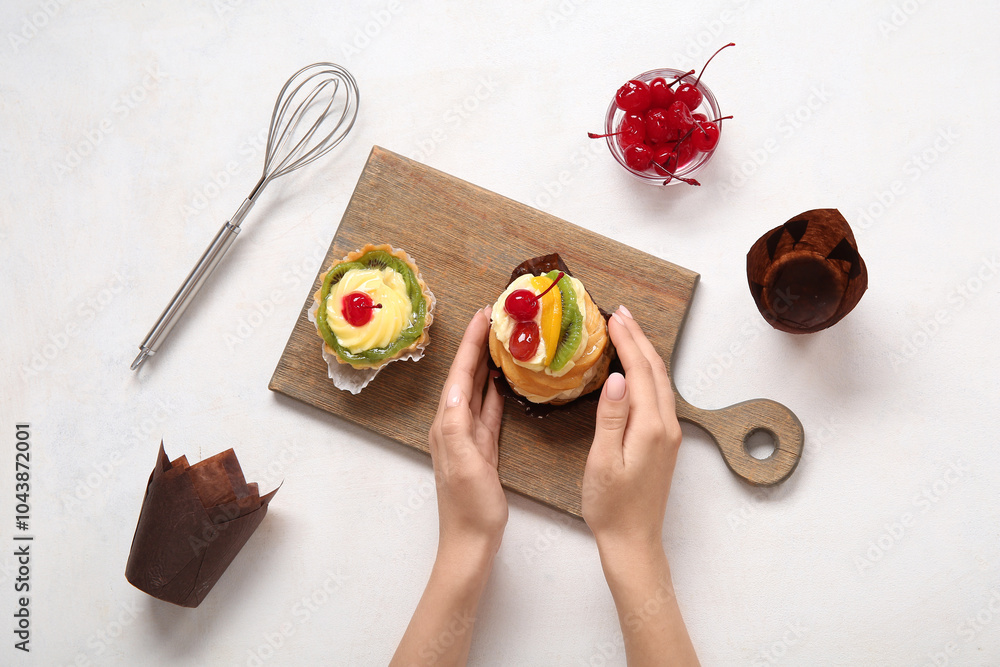 Female confectioner with tasty cakes on white background