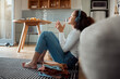 © peopleimages.com - Woman, headphones and home with music, chores break and morning on floor with rest in living room. Audio, coffee and hot drink with listening, podcast and home cleaning on relax weekend in break
