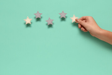 Female hand with five stars rating on turquoise background. Customer experience concept