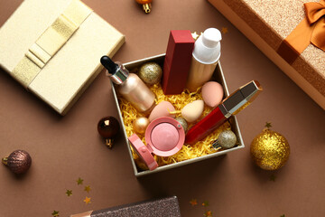 Christmas composition with different makeup products in gift box on brown background, closeup