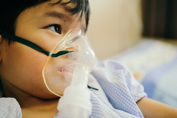 Boy 4 years old , inhale medication by inhalation mask to cure Respiratory Syncytial Virus (RSV) on hospital bed. Admitted patient boy inhalation therapy.