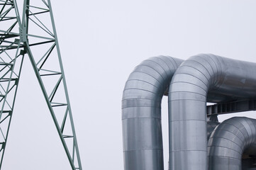 The photo shows a pipeline and a power line close-up against a gray sky