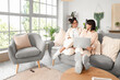 © Pixel-Shot - Young lesbian couple using laptop on sofa at home
