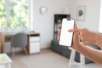 Poster - Woman holding mobile phone with blank screen in living room