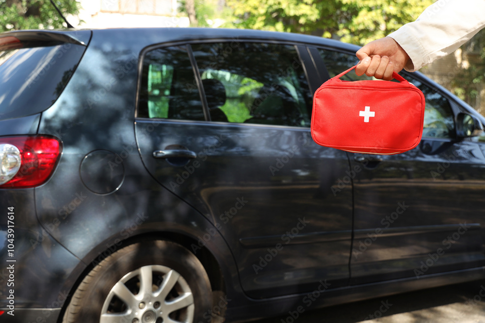 Man holding first aid kit near car outdoors