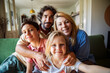 © Marko Geber - Happy family taking group selfie on couch at home