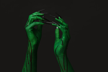 Green hands of witch on black background. Halloween celebration