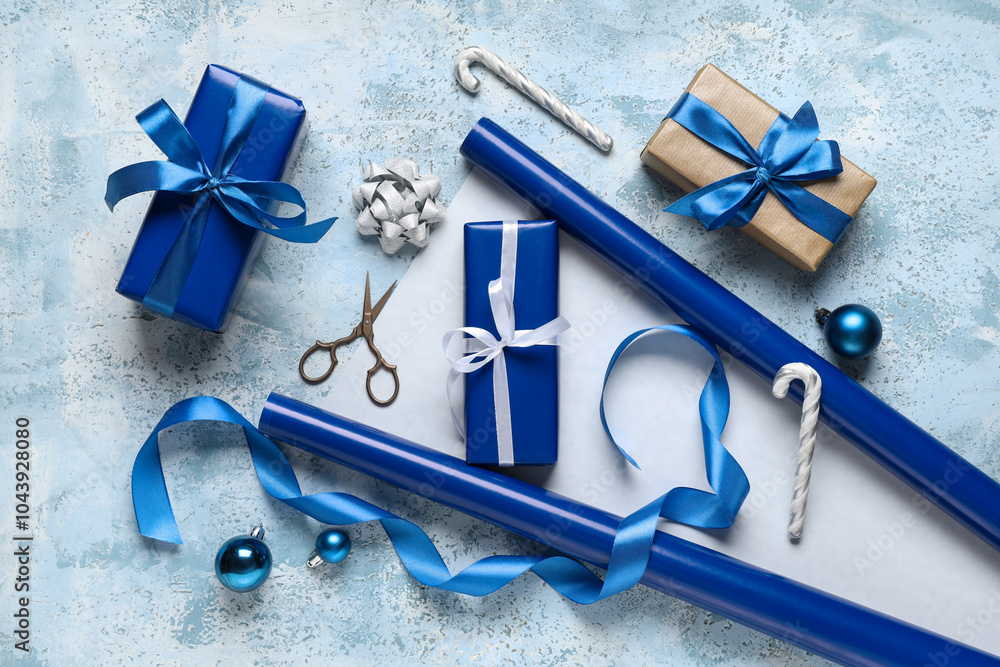 Christmas gift boxes with packing materials and different decorations on grunge blue background