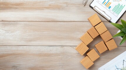 A flat lay of wooden blocks forming a rising arrow on a textured surface, with a chart and potted plant nearby, symbolizing growth and progress.