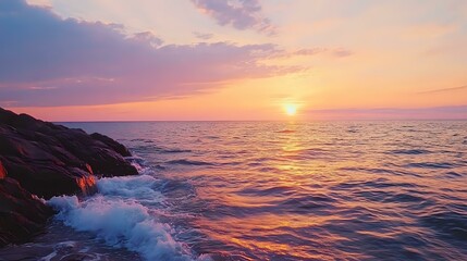 Wall Mural - golden sunset over a calm ocean, with soft waves lapping at a rocky shore and the sky painted in sha