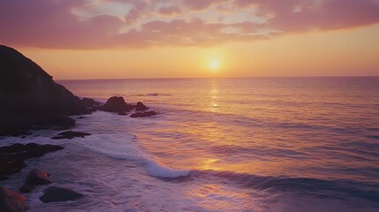 Wall Mural - golden sunset over a calm ocean, with soft waves lapping at a rocky shore and the sky painted in sha