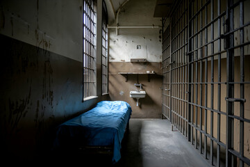 Dimly lit prison cell with bed conveys somber atmosphere