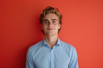 Confident Young Man in Blue Shirt Against Vibrant Red Background for Portrait Photography