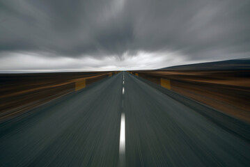 Blurred Iceland asphalt road and dark thunder clouds over it