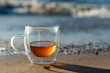 © Андрей Знаменский - Glass mug with hot drink standing on the sea shore