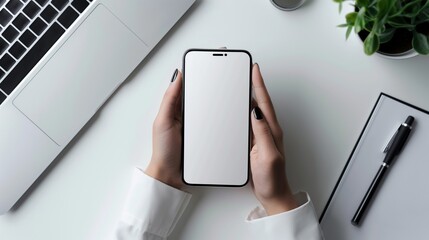 Wall Mural - Hands holding smartphone with blank screen mockup at office workspace desk. Laptop, plant, gadget in workplace. Mobile phone template advertising image. Mock up product photorealistic