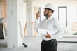 © Serhii - Portrait of young handsome Indian male civil engineer or architect wearing helmet at construction site