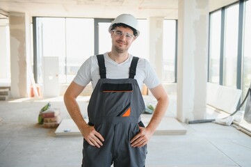 Wall Mural - Handsome young male builder in hard hat, while working at construction site.