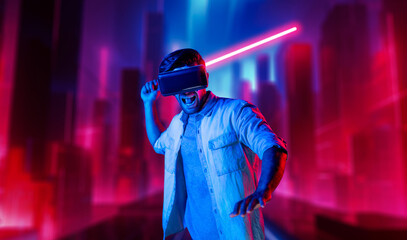 Gamer holding laser sword and playing action game while wearing VR glasses. Caucasian man using visual reality headset while standing and surrounding by neon castle. Innovation technology. Deviation.