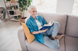 © deagreez - Portrait of nice aged woman enjoy read book wear blue shirt bright interior flat indoors