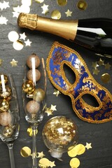 Poster - Beautiful golden carnival mask, bottle of sparkling wine, glasses with decorative balls and confetti on gray textured table, flat lay