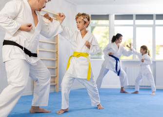 Wall Mural - Father and son karatekas in kimonos practice karate fighting in studio