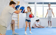 © JackF - Young girl with her trainer father at gym. Boy wearing boxing gloves exercise and punch to pads for boxing