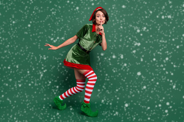 Wall Mural - Full length body size view of attractive mysterious funny girl elf showing shh sign isolated over green color background