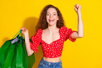 Wall Mural - Photo portrait of lovely young lady shopping bags winning dressed stylish red garment isolated on yellow color background