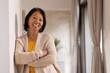© Wavebreak Media - Smiling Asian senior woman in cozy sweater leaning against wall at home
