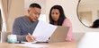 © Wavebreak Media - Multiracial senior couple reviewing documents on laptop together at home, focused and engaged