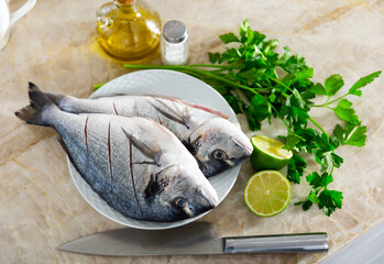 On cutting board are two silver dorado fish, prepared for frying