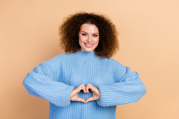 Canvas Print - Portrait photo of young positive woman wearing blue knitted sweater showing heart symbol donator isolated on beige color background