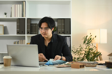 Architect using laptop and reviewing color samples for a project at his office