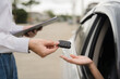 © Nittaya - Car Key Handover:  A close-up shot of a car key being exchanged between a salesperson and a customer, symbolizing a successful car purchase or rental.
