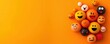 © Kasitthanin - Colorful smiley balls on vibrant orange background, joyful theme.
