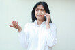 © M Alfan Setyawan - image of clueless asian young business woman raising palms worried speaking on smartphone wear white formal shirt, have no idea gesture questioning solution, frustrated expression, standing