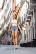 © JoseIMartin - Young woman walks through a charming narrow street, looking up at towering buildings in a bustling city