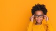 © Anna - Smiling child wearing glasses against vibrant yellow background