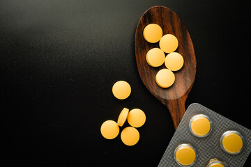 Pills Medicine tablet capsules blister pack in wooden spoon on a black background