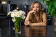© Cavan Images - Solitude blond woman sitting at the table with flowers