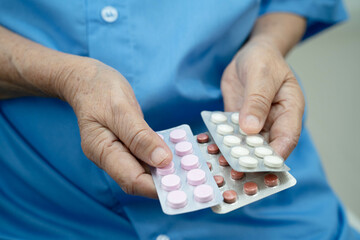 Asian elderly woman holding pill drug in hand, strong healthy medical concept.