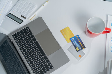 Businessman is using a laptop and credit cards to shop online at his desk. The image evokes concepts such as e-commerce, online payment and finance