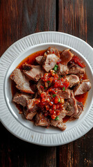 Wall Mural - Grilled pork loin slices served on white plate with spicy tomato salsa, shot from above on dark rustic wooden background