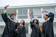 © Kawee - Group of diverse students celebrating college achievement outside campus.