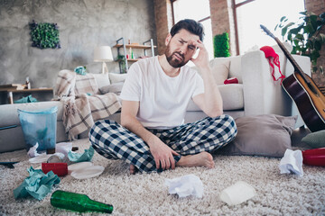 Full size photo of attractive young male stressed hangover dressed sleepwear wake up after party day messy light home interior living room