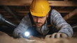 © Marketplace - A man in a hard hat inspects an attic or crawl space using a flashlight, showcasing safety and maintenance in construction work.